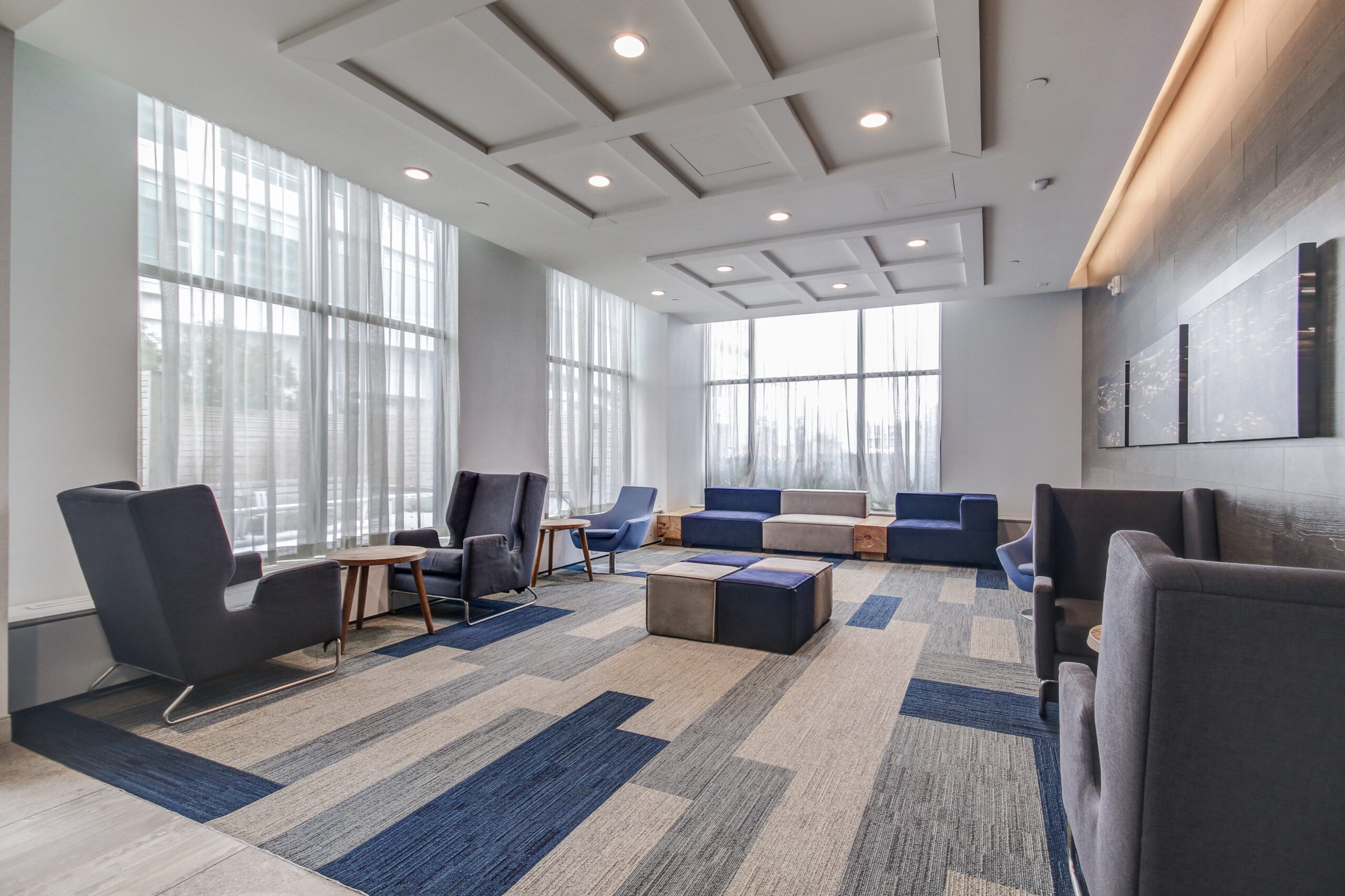 Render of Evolv Lobby. Man sitting at a desk with his laptop. A couple are walking toward the entrance.