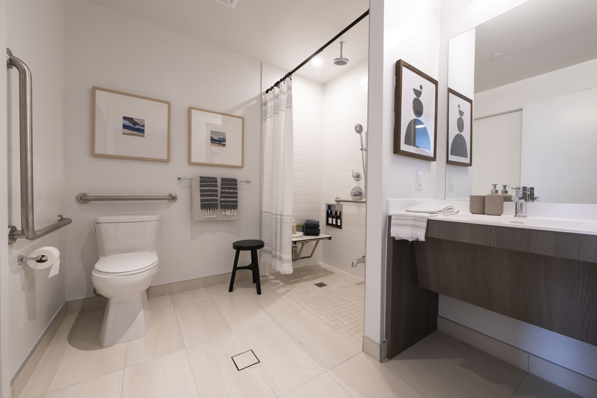 Accessible bathroom with under knee clearance, roll-in shower, grab bars and ceiling mounted shower head