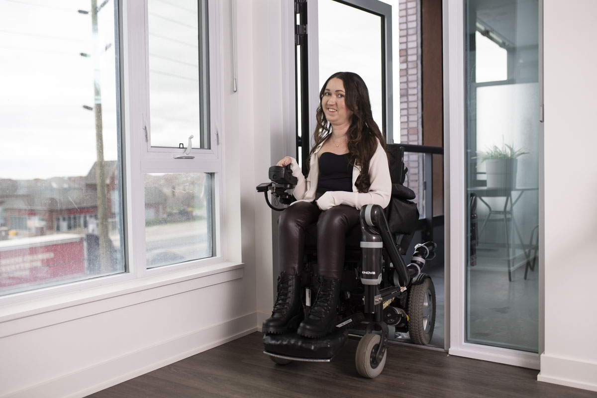 Woman in wheelchair using the roll out balcony in accessible condo suite